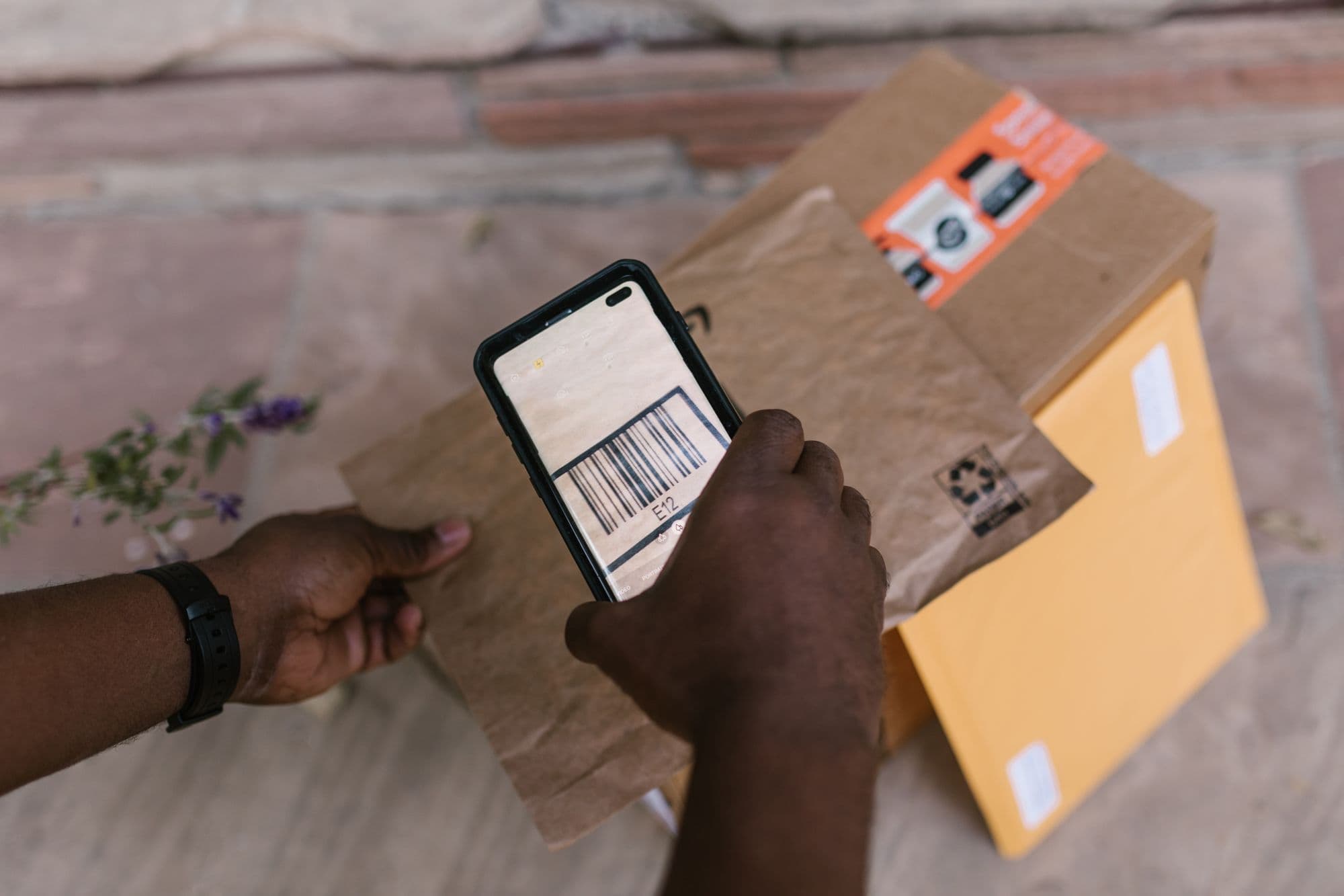 Χέρια σκανάρουν με το κινητό το barcode ενός δέματος